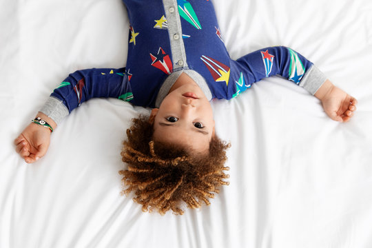 Boy lies upside down on bed