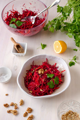 Healthy raw vegan beetroot salad with carrot and walnuts in a bowl on white wooden table. Natural organic food concept. Healthy diet