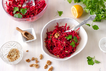 Healthy raw vegan beetroot salad with carrot and walnuts in a bowl on white wooden table. Natural organic food concept. Healthy diet