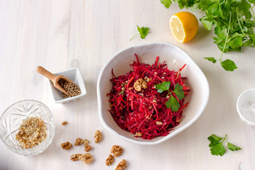 Healthy raw vegan beetroot salad with carrot and walnuts in a bowl on white wooden table. Natural organic food concept. Healthy diet