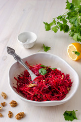 Healthy raw vegan beetroot salad with carrot and walnuts in a bowl on white wooden table. Natural organic food concept. Healthy diet