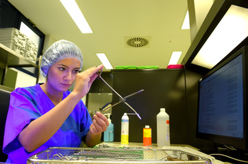 A young woman works in a hospital as a  medical hygiene technician. She is dressed  in special medical hygiene clothing and  carries out hygiene disinfecting and logistic tasks.