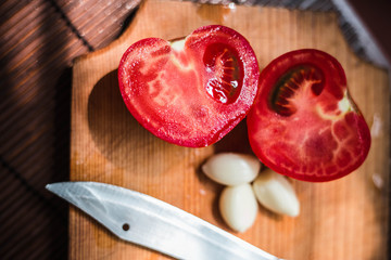 Wooden board for cooking and knife. Sliced tomatoes with garlic