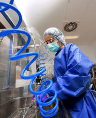 A young woman works in a hospital as a  medical hygiene assistant. She is dressed  in special medical hygiene clothing and  carries out hygiene disinfecting and logistic tasks.
