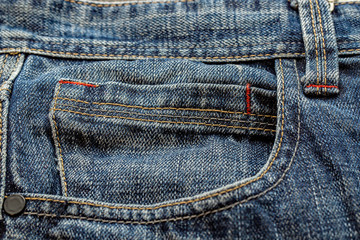 Close up of the front pocket of a pair of washed out blue denim pants