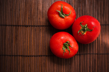 tomatoes on a bamboo board. Juicy vegetables on a brown background