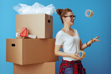 woman near cardboard box throwing up adhesive tapes on blue