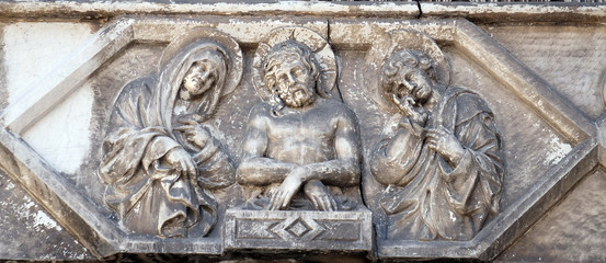 Jesus bound with the Virgin Mary and St. John on the portal of the Cathedral of S.Martino in Lucca, Italy