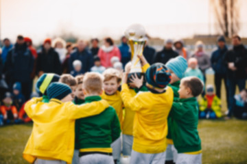 Blurred Background of Kids Sport Team with Trophy. Kids Celebrating Football Championship. Happy Young Soccer Players Holding Golden Cup. Football Team Winning Youth Soccer Tournament