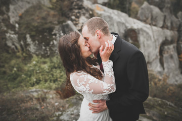 Happy beautiful wedding couple bride and groom at wedding day outdoors on the mountains rock. Happy marriage couple outdoors on nature, soft sunny lights