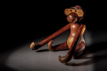A wooden toy figure of a monkey in the dual spotlight