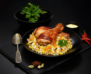 grilled chicken legs with sesame and rice on a black background.