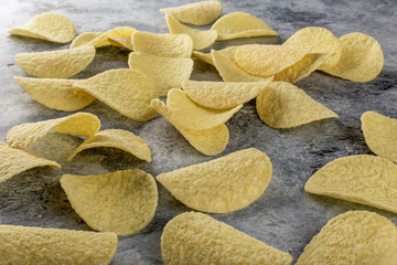 Potato chips on grey concrete table. Concept of fast food and snacks.