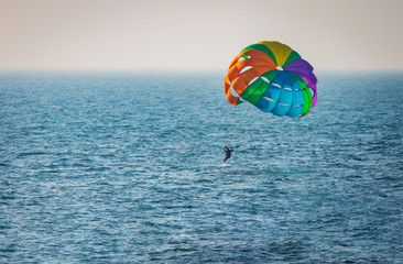 amazing shot at sunset of Parasailing water amusement - flying on a parachute behind a boat on a summer holiday by the sea in the resort Baga beach Goa India India watersports