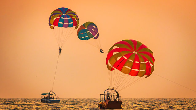 amazing shot at sunset of Parasailing water amusement - flying on a parachute behind a boat on a summer holiday by the sea in the resort Baga beach Goa India India watersports