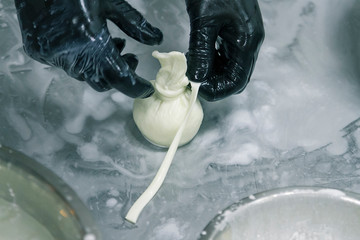 The process of making burrata cheese on a metal table in a cheese factory