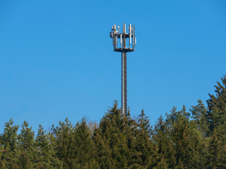 Cellular tower for mobile phone LTE 4G in the forest blue sky background