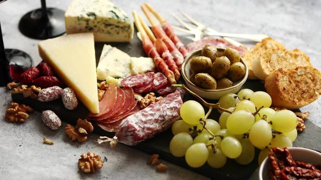 Cold snacks board with meats, grapes, wine, various kinds of cheese