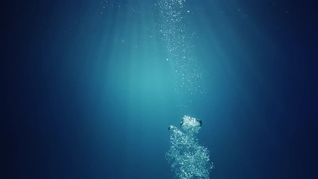 Sun light beams shining from above coming through the deep crystal clear blue water causing a beautiful water lighting reflections curtain with air bubbles rising up to the surface