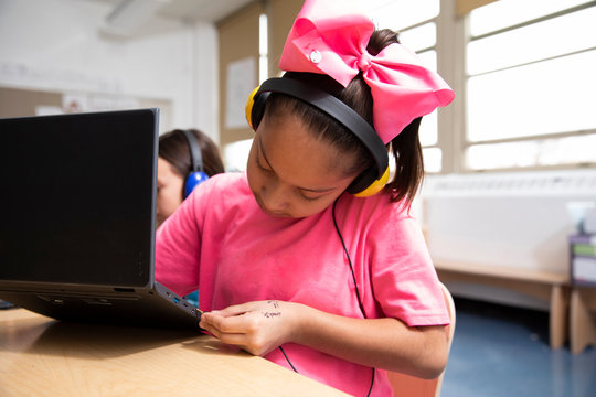 Girl plugging headphones into laptop