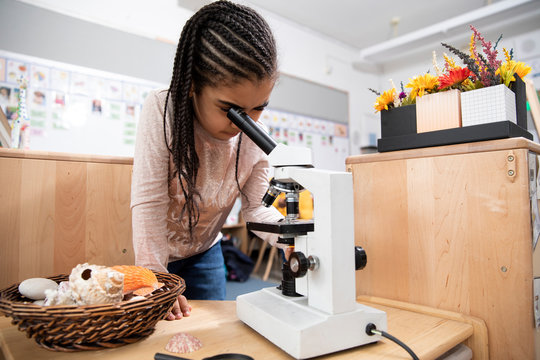 Girl using microscope in classroom
