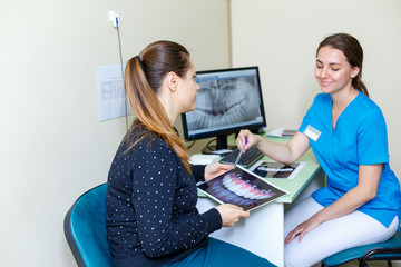Young woman Dentists and woman patient discussing the x-ray photograph on computer treatment discussion close up