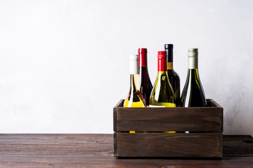 Set of different kinds bottles of champagne, white, red wine in wooden box on light background - Powered by Adobe