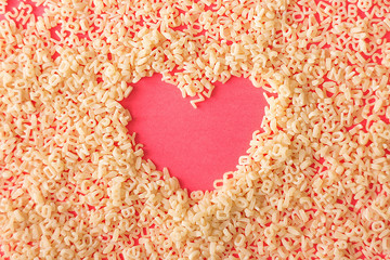 bright pink background with pasta. letters out of pasta. heart of pasta
