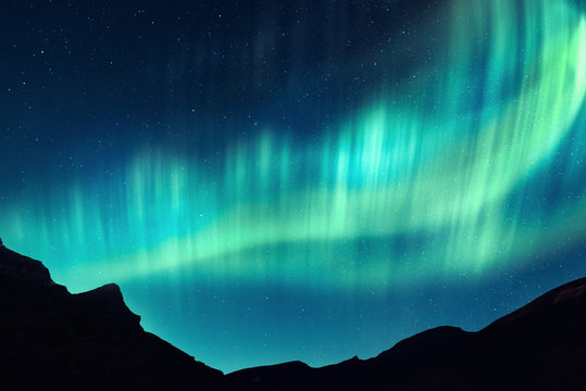 Aurora borealis. Northern lights in winter mountains. Sky with polar lights and stars
