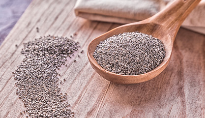 Chia seeds in wooden spoon on table.