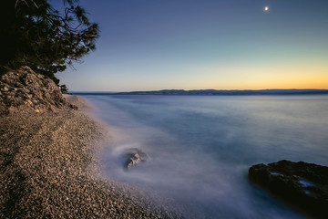 Vacation in Croatia. Pebble beach and the waves. Long exposure. Sunset in Dalmatia.