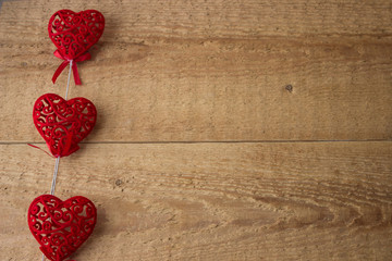 Three red hearts on a wooden background.
