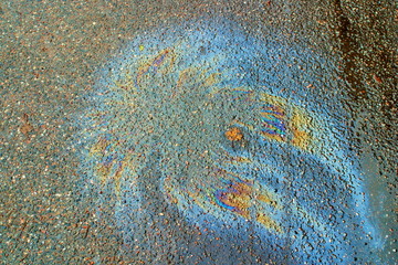 Image of rainbow gasoline spot on the asphalt in the form of jellyfish