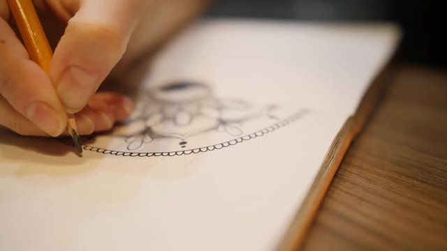 Female hands marking on a paper for drawing mandala in scketch book. Close up shot