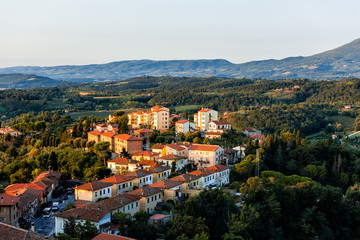 Fototapeta premium Chiusi village cityscape at sunrise in Umbria Italy with rooftop houses on mountain countryside and rolling hills