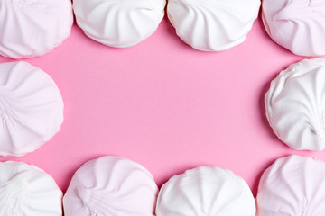 marshmallow and candy hearts on a pink background with copy space