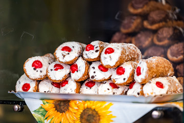Closeup of chocolate cherry cannoli stuffed with cream cheese whipped filling dessert on tray window display in gourmet bakery Italian cafe with crust