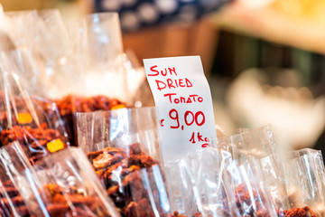 Food market with stall and sun dried tomato sign with price on retail display closeup per kilogram packaged vegetables