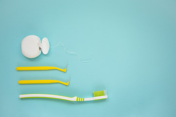 Teeth care, toothpaste, toothbrush and dental floss on blue background. Teeth cleaning brushing and flossing.