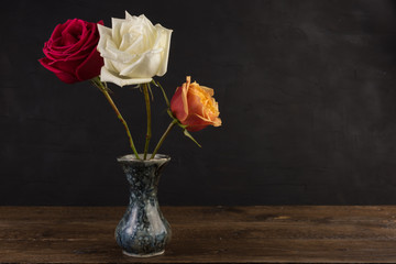 Small marble vase with bunch of roses flowers on black background