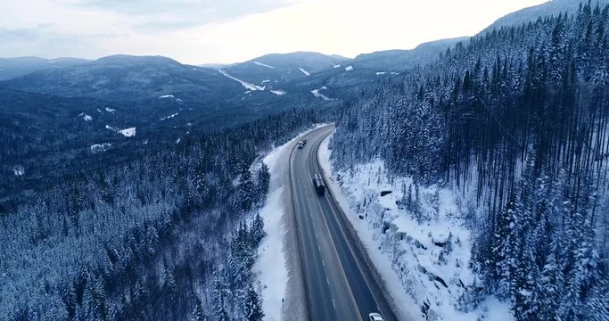 Big trucks pass on a highway in a Canadian natural park.