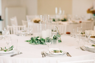 Wedding dinner table set. Classy white decor with greenery