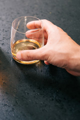Male hand grasping a glass with whisky.