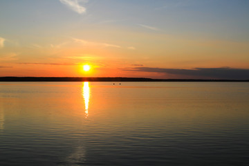 Fototapeta premium Fishermen float on a lake at sunset