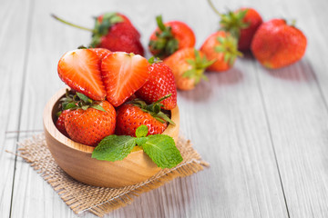 Fresh strawberries in a bowl on wooden table .