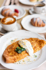 Breakfast. Frittata - italian omelet. Omelette with tomatoes, avocado, spinach and soft cheese. Croissants, coffee and other dishes on the table in the restaurant