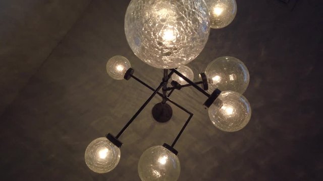 Decorative lighting bulbs hanging on ceiling. Bright glowing light from vintage bulbs lamp. Antique tungsten light lamp on ceiling in dark room. Lighting interior design. Vintage chandelier decor