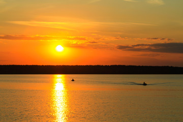 Fishermen float on a lake at sunset