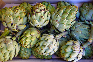 Obraz premium Green and purple artichokes at a farmers market