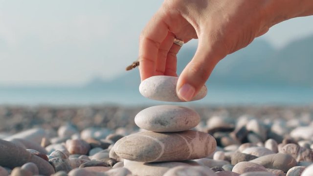 Hand making stone tower on sea beach. Meditation at summer holidays